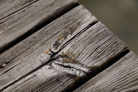 Old wooden planks with knotholes of a pier over lake waterの写真素材