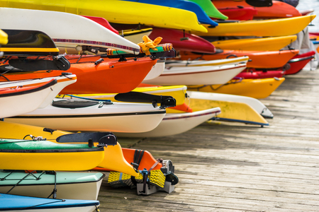 Colorful canoes and kayaks by the lake on a sunny day. Used for summer boating and recreational sport activities on water.の写真素材
