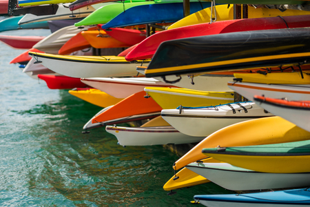 Colorful canoes and kayaks by the lake on a sunny day. Used for summer boating and recreational sport activities on water.の写真素材