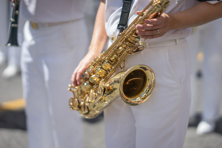 Saxophone player in a military or marching band playing during a parade or festival on a sunny day....
