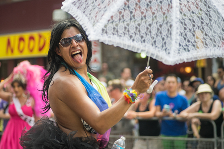 June 29, 2014, Toronto, Canada. Performer marching in the Toronto Pride Parade wearing rainbow flag. Caring a lace umbrella with a cheerful expression. Supporting marriage equality and LGBT rights.のeditorial素材