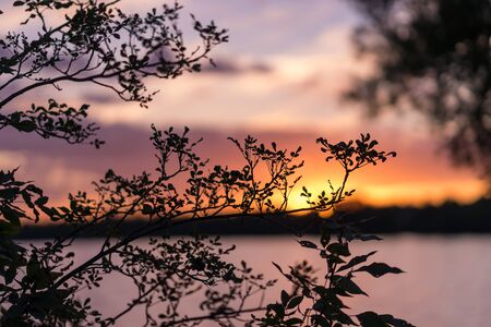 Beautiful summer sunset with a colorful sky and clouds, reflection on the surface of the lake. Relaxing cottage weekend.の写真素材