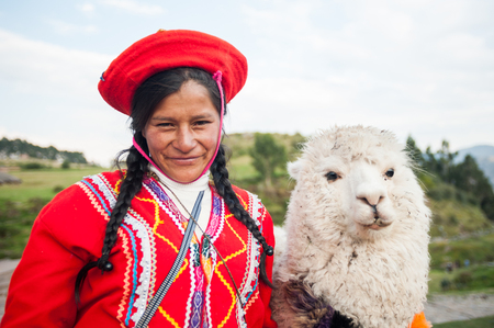April 22, 2014. Saqsaywaman Ruins near Cusco, Peru. Indigenous woman posing with a llama. She is wearing colorful traditional clothing.のeditorial素材