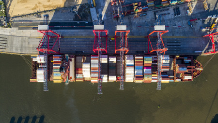 Aerial view with the ship's container of the drone is loading in a harbor. Cenital plane.