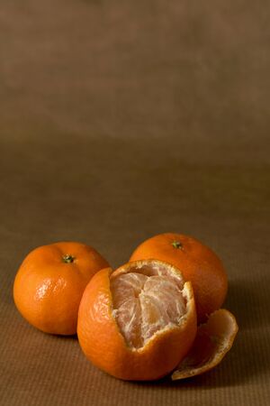 Close-up of three clementines on brown paperの写真素材
