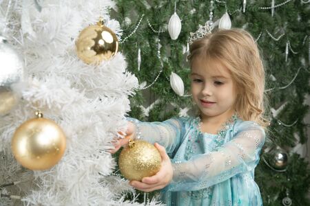 Happy little girl with Christmas tree toy near the Christmas treeの写真素材