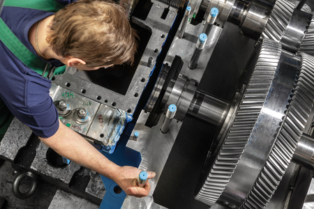 Working man with a small steam turbine. Metal gears. Gear wheels of the engine.の写真素材