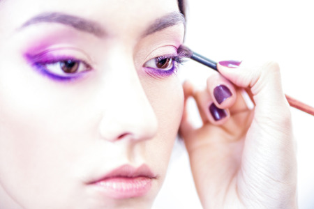 Stylist hand applying eyes make-up to the eyelids of a young beautiful model.の写真素材