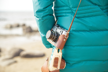 Woman photographer with old camera on the ocean. View from the back. Close-up.の写真素材