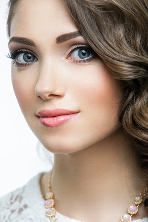 Portrait of beautiful woman model with big blue eyes and romantic wavy hairstyle. Sexy glossy lips makeup and dark eyebrows. Isolated on white background.の写真素材