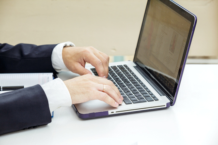 Businessman typing on a laptop. The man in a suit and a white shirt. Closeup.の写真素材