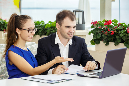 Businessman and business lady at a meeting. They are discussing the contract. The man in a suit and a white shirt. The woman in a blue blouse and glasses. Woman showing something on the laptop.の写真素材