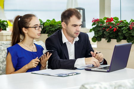 Businessman and business lady at a meeting. They are discussing the contract. The man in a suit and a white shirt. The woman in a blue blouse and glasses.の写真素材