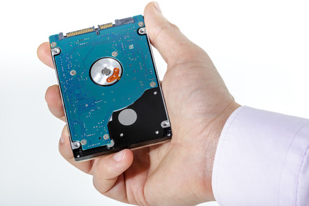 Man's hand holds a 2.5 inch hard drive. View of the backside HDD, from the PCB. Isolated on white...