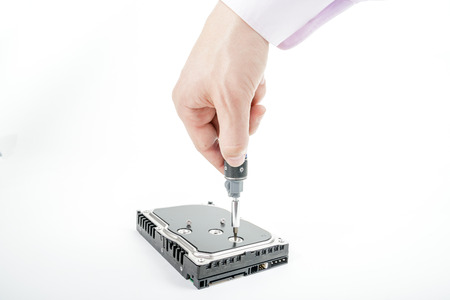 Hand repairman unscrews the 3.5 inch hard drive cover with a screwdriver. Isolated on white background.の写真素材