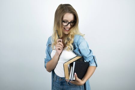 blonde young smart woman in glasses holding books and pen white backgroundの写真素材