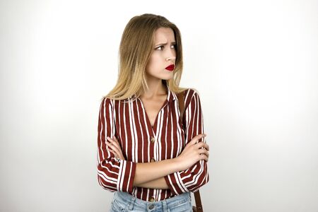 young beautiful blonde upset woman wearing trendy striped shirt denim shorts and leather mini bag isolated white backgroundの写真素材