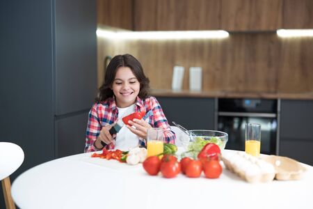 cute teen daughter helping to cook breakfast in the kitchen looking happyの写真素材