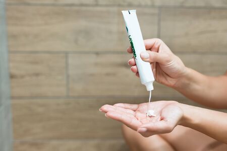 woman squeezing lotion onto her hand in the showerの写真素材