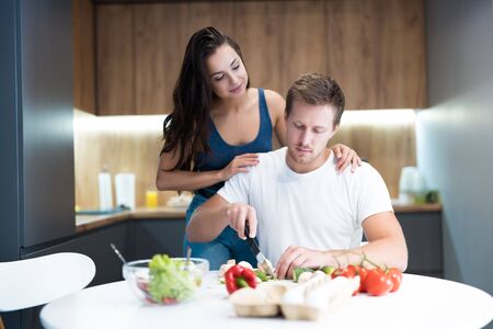 young couple cooking breakfast in the kitchen together wife hugging her beloved husband family traditionsの写真素材