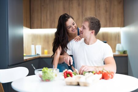 young couple cooking breakfast in the kitchen together beautiful wife hugging her beloved husband family traditionsの写真素材