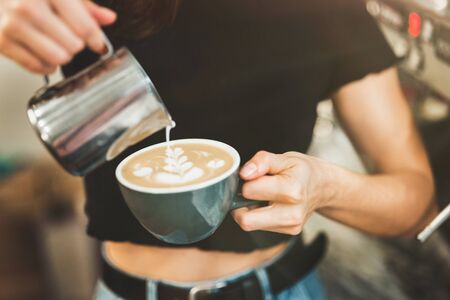 process of pouring whipped milk to hot coffee drink, barista work.の写真素材