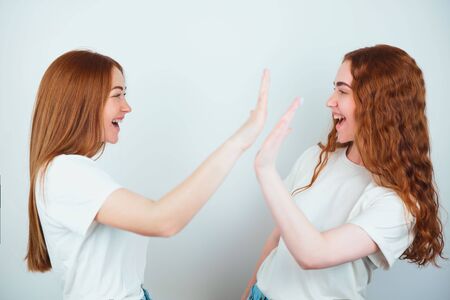 two redheaded young women both wearing t-shirts standing on isolated white backgroung look positive...