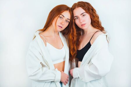 portrait of two redheaded young women both look stylish both wearing casual shirts standing on isolated white backgroung, beauty and style conceptの写真素材