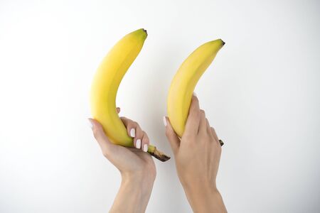 image of woman's hands holding fresh bananas on isolated white background.の写真素材