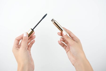 woman's hand holdingeye maskara to apply on lashes, isolated white background, makeup and beauty concept.の写真素材