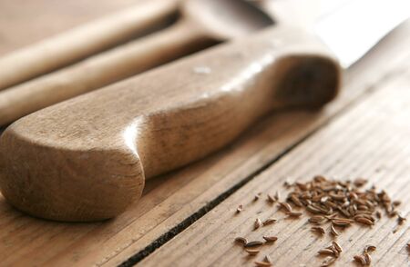 Old knife and cumin on wooden table