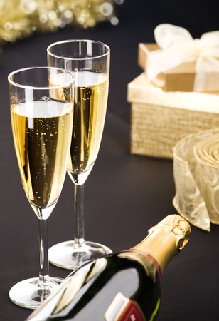Two flutes and bottle of champagne  Golden gift box and transparent ribbon in background  All on matt black  の写真素材