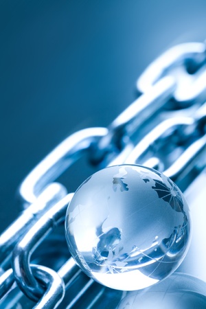 Abstract chain and globe made of glass in blue ambient light の写真素材