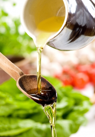 Pouring oil in the salad over a wooden spoonの写真素材