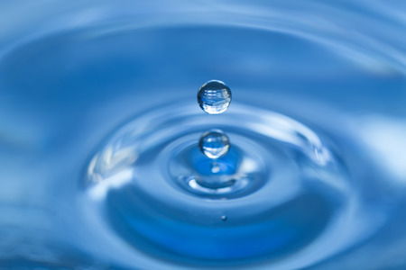 Water drop falling into water making a perfect droplet splashの写真素材