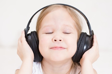 portrait of adorable smiling little girl in headphonesの写真素材