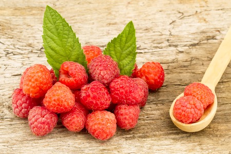 ripe raspberries with mint leaves closeup on wooden background, top viewの写真素材