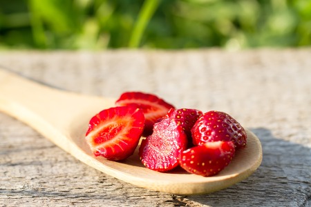 ripe fresh strawberries in spoon on wooden background, close upの写真素材