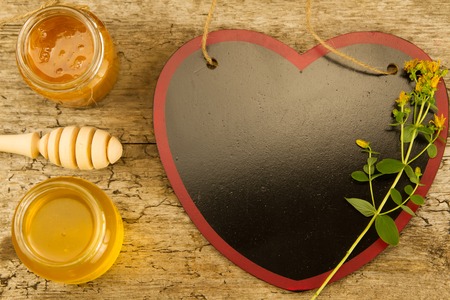 two small jars of fresh honey with drizzler, cinnamon, flowers on wooden background, top viewの写真素材