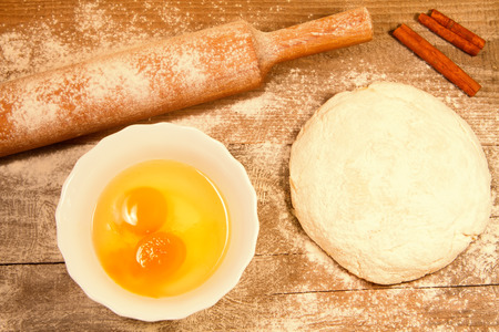 homemade baking. Fresh dough for pastry, stick cinnamon,  flour, spilled flour, broken eggs on a chopping old Boardの写真素材
