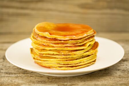 a stack of pancakes on a white plate with jam on wooden backgroundの写真素材