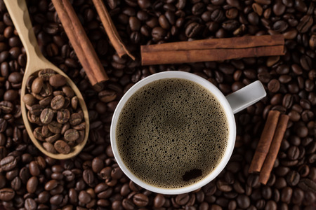 Cup of freshly brewed French coffee with cinnamon sticks and a wooden spoon on a background of beansの写真素材