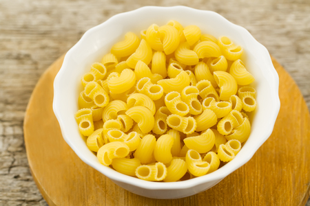 raw pasta in a white plate on cutting Board on wooden background. A healthy dietの写真素材