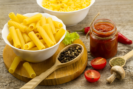 Ingredients for cooking pasta on wooden background. Chile pepper, cherry tomatoes, spices, mushrooms, tomato sauce. Healthy nutrition.の写真素材