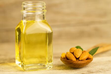 peeled almonds in a spoon and oil in a jar on wooden backgroundの写真素材