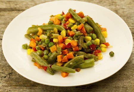 mixed vegetables on white plate on wooden backgroundの写真素材