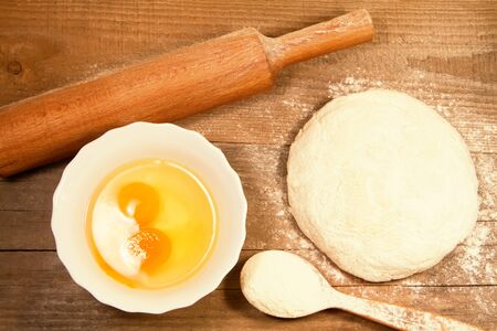 homemade baking. Fresh dough for pastry, kitchen rolling pin, spoon flour, broken eggs on a chopping old Boardの写真素材