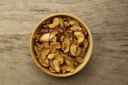 bunch of dried apples in a bowl on old wooden background. Top viewの写真素材