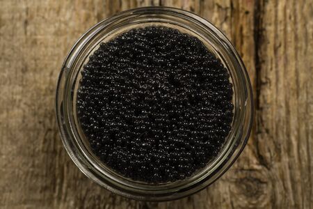 black Beluga caviar in glass jar on wooden backgroundの写真素材