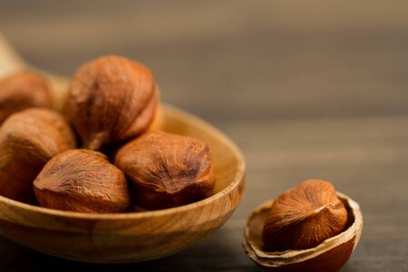Peeled hazelnuts in wooden spoon on wood background.の写真素材